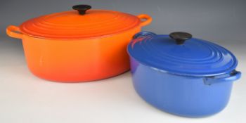 Two Le Creuset twin handled casserole dishes in orange and blue, one marked 'F', the other '35',