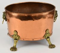 Copper log bin with twin lion mask handles, raised on pad feet, W42 x H30cm