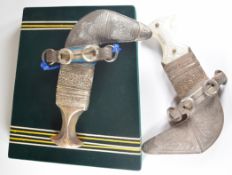 Two presentation Jambiya daggers, both with ornate white metal decoration to the scabbards, one with