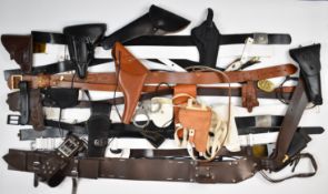 A collection of leather pistol and revolver holsters and belts including some with named metal
