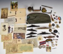Collection of military ephemera including silver wound badge, cap badges, pieces of shrapnel,