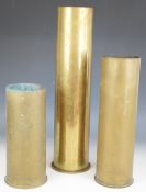 Three brass shell cases including a German WW1 dated 1917 and one 105mm example, tallest 50cm