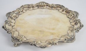 George V hallmarked silver salver with shaped edge, raised on three scroll feet, Chester 1915,