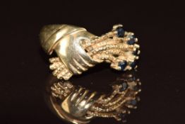 A 9ct gold ring set with sapphires in the form of a hand holding flowers, 2.9g, size N