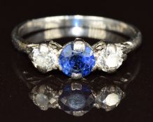 A platinum ring set with a round cut sapphire of approximately 0.5ct and two diamonds each