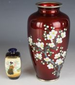 Two Japanese vases comprising a cloisonné example with cherry blossom decoration over a red