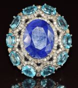 A white metal ring set with an oval cut tanzanite (13.05ct) surrounded by apatite (4.34ct) and