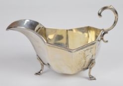 Edward VII hallmarked silver octagonal sauce boat with scroll handle, raised on three hoof feet,