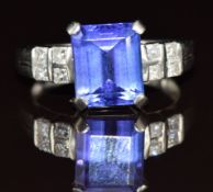 A platinum ring set with an emerald cut tanzanite of approximately 3.4ct and four princess cut