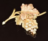 An 18k gold bi-coloured brooch in the form of a bunch of grapes with textured leaves and set with