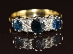 An 18ct gold ring set with three oval cut sapphires and four diamonds, 3.8g, size N