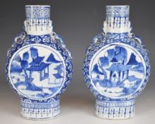 A pair of 19th / 20thC Chinese blue and white twin handled moon flasks, decorated with figures in
