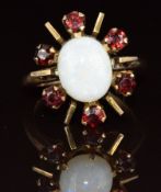A 9ct gold ring set with an oval opal cabochon surrounded by garnets, 6.4g, size O