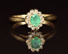 A 14k gold ring set with an oval cut emerald of approximately 0.4ct surrounded by diamonds, 2.6g,