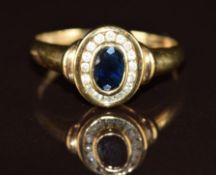 A 9ct gold ring set with an oval cut sapphire of approximately 0.5ct surrounded by diamonds, 2.1g,