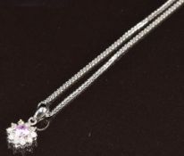 An 18ct white gold pendant set with a pink sapphire surrounded by diamonds, on 18ct white gold