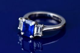 A platinum ring set with an emerald cut sapphire of approximately 1.8ct and two emerald cut diamonds