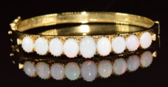 A yellow metal bangle set with nine oval opal cabochons, in antique Searle & Co bangle box, 13.4g,