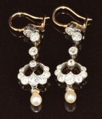 A pair of c1915 yellow metal earrings set with diamonds in a platinum setting with natural drop