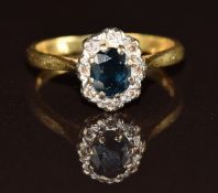 An 18ct gold ring set with an oval cut sapphire surrounded by diamonds, 2.7g, size J