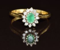 An 18ct gold ring set with an oval cut emerald surrounded by diamonds, 3.2g, size L