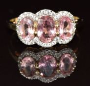 A 9ct gold ring set with three oval cut pink tourmalines surrounded by cubic zirconia, 2.6g, size P
