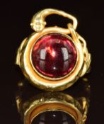 Victorian yellow metal ring set with a garnet cabochon within a serpent border, 5g, size I