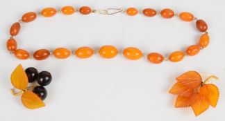 An amber necklace made up of twenty one oval beads and two amber brooches