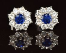 A pair of 18ct white gold earrings each set with a sapphire of approximately 0.15ct surrounded by