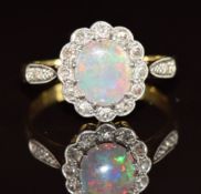 A c1930 18ct gold ring set with an opal cabochon surrounded by diamonds in a platinum setting, 2.8g,
