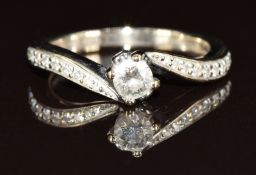An 18ct white gold ring set with a 0.21ct round cut diamond and further diamonds to the shoulders