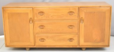 Ercol mid century modern light elm sideboard with three straight drawers flanked by two cupboards,