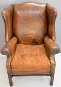 Leather wing back armchair raised on straight mahogany legs, H109cm