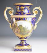 Crown Derby 19thC twin handled pedestal vase with decoration of a landscape scene of thatched