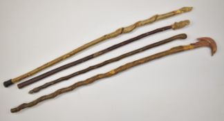 Four carved walking sticks with various finials including an owl, rabbit and a bird, one with