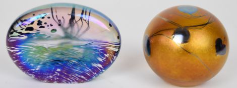 Two John Ditchfield for Glasform iridescent glass paperweights, one with stylised landscape scene