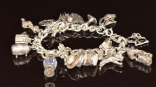 A silver charm bracelet with 18 silver charms including car opening to reveal two horses, boat,
