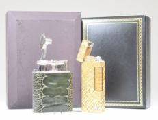 Two Dunhill lighters in original boxes, one a gold plated Rollagas example the other with fish