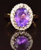 An 18ct gold ring set with an oval cut amethyst surrounded by diamonds, 4.9g, size K