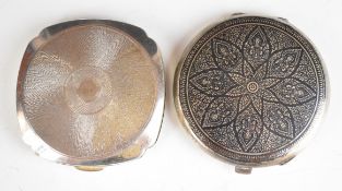 Two silver compacts comprising a Niello decorated example marked sterling silver, diameter 8cm and a