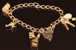 A 9ct gold charm bracelet made up of twisted oval links with five charms including three keys and '