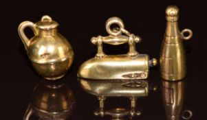 Three yellow metal charms, in the form of an iron, pot and Champagne bottle