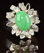 A white metal ring set with a jadeite cabochon and diamonds in a floral setting, marked 18k, 6.9g,