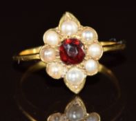 An 18ct gold ring set with a garnet surrounded by split pearls, 2.6g, size L