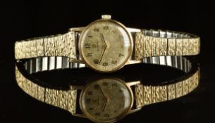 Omega 9ct gold ladies wristwatch with black hands, gold Arabic numerals, champagne dial and