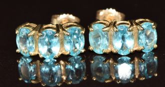 A pair of 9ct gold earrings each set with three oval topaz, 2.7g