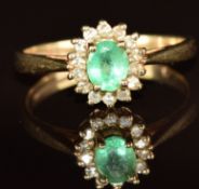 A 9ct gold ring set with an oval cut emerald of approximately 0.4ct surrounded by diamonds, 2.1g,