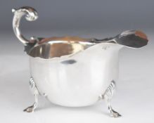 Large Victorian hallmarked silver sauce boat with shaped edge, scroll handle and raised on three