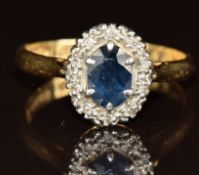 An 18ct gold ring set with an oval cut sapphire surrounded by diamonds in a platinum setting, 3.