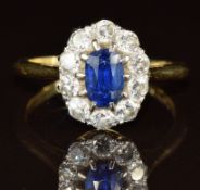 An 18ct gold ring set with an oval cut sapphire of approximately 0.5ct surrounded by diamonds in a
